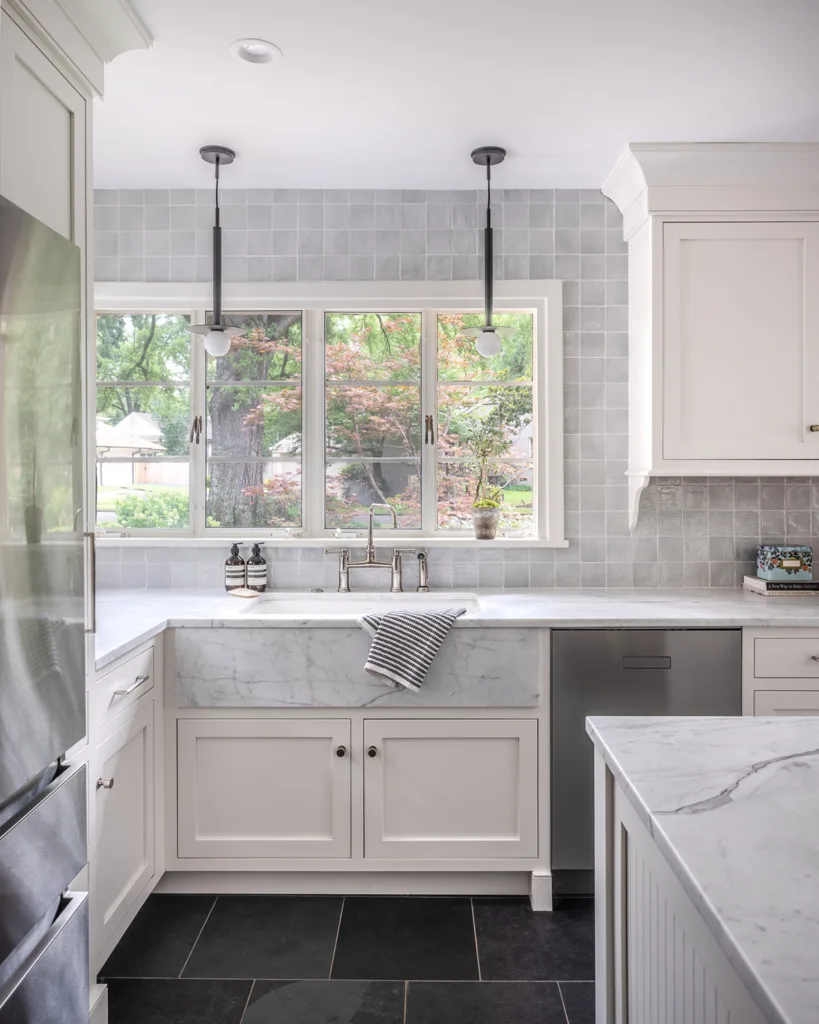 White painted inset kitchen cabinets with lots of natural light and a tiled kitchen wall
