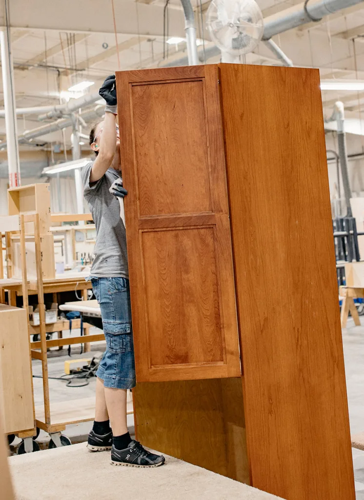Worker in the cabinet shop with pantry cabinets